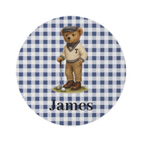 Personalized round rug with a golfing teddy bear on a blue gingham ground and the name James below, shown flat