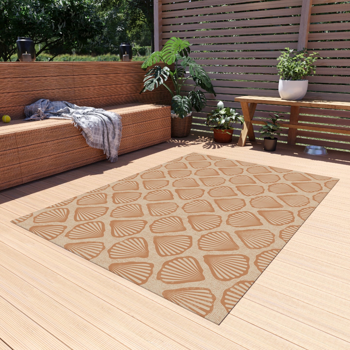 Sea Shell outdoor rug on a wooden deck beside a built-in bench and planters