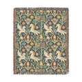 A square woven textile with fringe on all sides, featuring a repeating pattern of cream-colored foxes, flowers, and foliage on a dark teal-blue background. The design has a vintage, tapestry-like appearance.