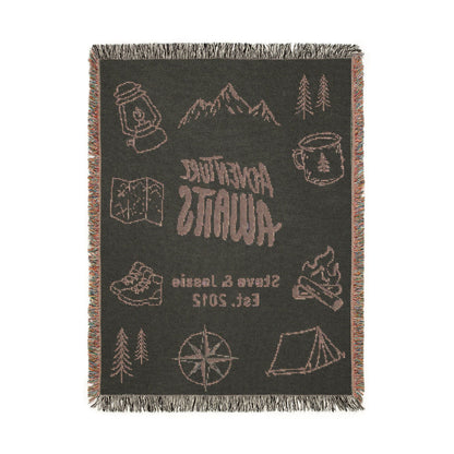 Back side of the Adventure Awaits personalized woven blanket, showing the design in reversed colors with light graphics on a dark charcoal ground