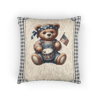 Woven pillow with a folk-art teddy bear in denim overalls holding an American flag and a drum, framed by a blue gingham border, front view