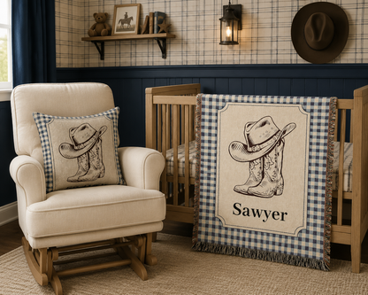 Cowboy baby woven pillow with a hat and boots on a blue gingham border, styled in a nursery
