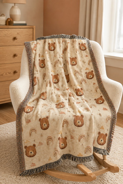 Bear and rainbow woven baby blanket over a cream armchair in a nursery