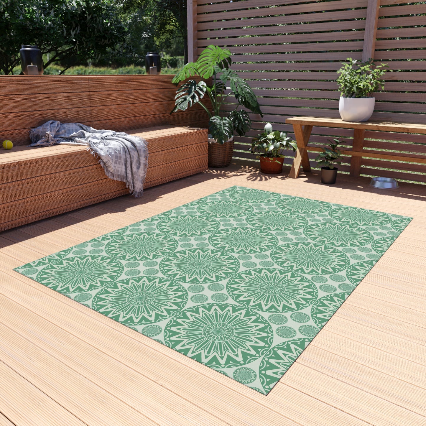 Sage green mandala outdoor rug on a wooden deck beside a built-in bench