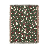 Fall woven blanket with red and cream toadstools on a deep forest green ground, shown flat