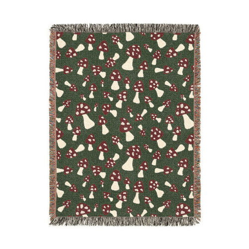 Fall woven blanket with red and cream toadstools on a deep forest green ground, shown flat