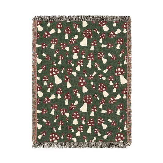 Fall woven blanket with red and cream toadstools on a deep forest green ground, shown flat