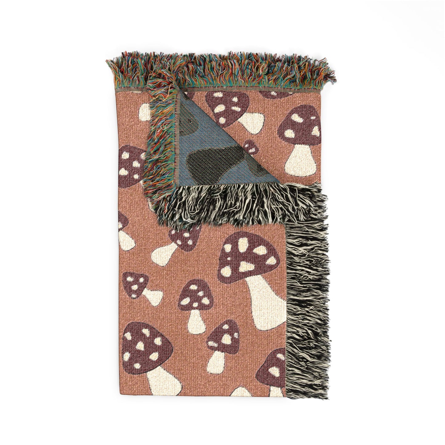 Folded Mushroom Terra woven blanket showing the fringed edge and the blue-grey reverse side