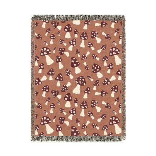 Fall woven blanket with cream and rust toadstools on a warm terracotta ground, shown flat