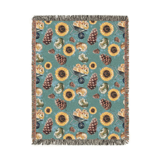 Fall woven blanket with sunflowers, pinecones and leaves on a muted teal ground, shown flat