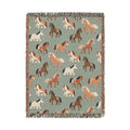 Sage green woven blanket with chestnut, rust and cream horses walking across it, shown flat