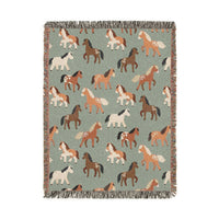 Sage green woven blanket with chestnut, rust and cream horses walking across it, shown flat