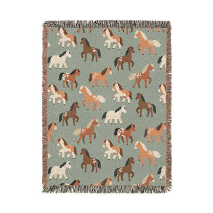 Sage green woven blanket with chestnut, rust and cream horses walking across it, shown flat