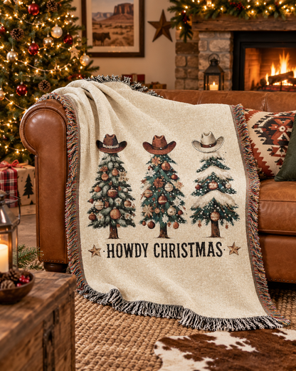 Howdy Christmas woven blanket draped over a brown leather armchair beside a lit Christmas tree