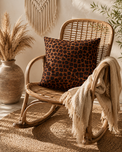 Leopard woven pillow on a rattan chair with pampas grass and a cream throw