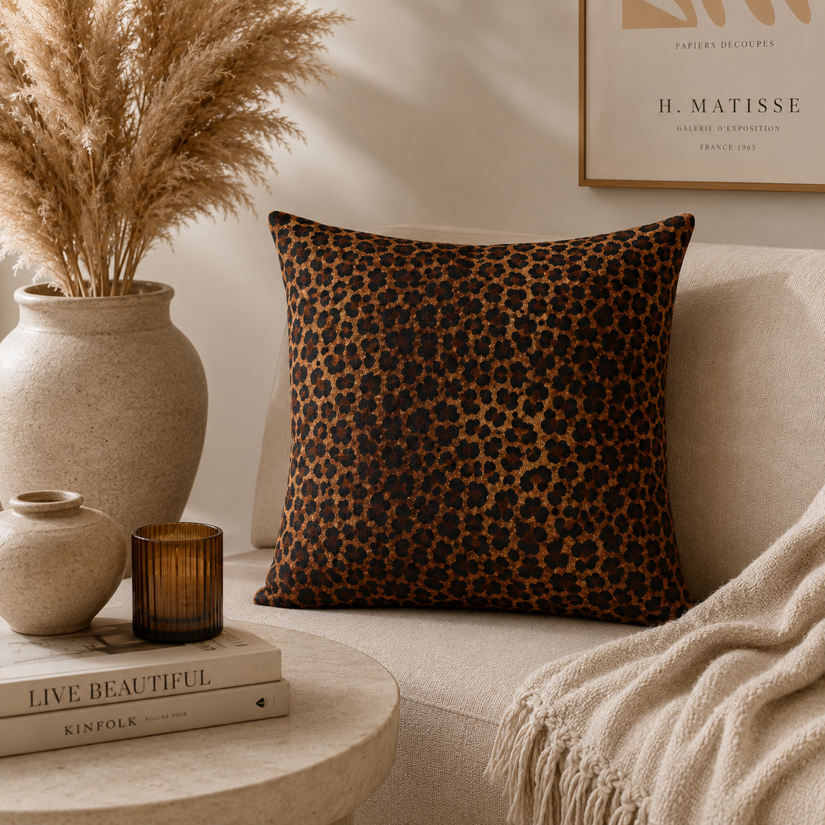 Leopard woven pillow on a cream sofa with candles and pampas grass