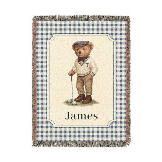 Personalized woven baby blanket with a golfing teddy bear and a name on a blue gingham border, shown flat
