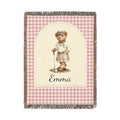 Personalized woven baby blanket with a golfing teddy bear and a name on a pink gingham border, shown flat