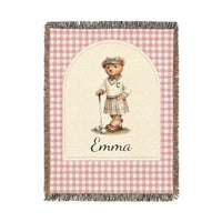 Personalized woven baby blanket with a golfing teddy bear and a name on a pink gingham border, shown flat