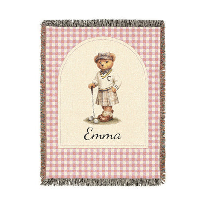 Personalized woven baby blanket with a golfing teddy bear and a name on a pink gingham border, shown flat