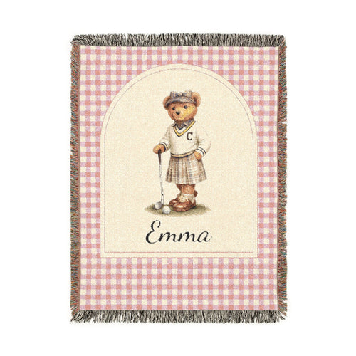 Personalized woven baby blanket with a golfing teddy bear and a name on a pink gingham border, shown flat