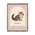 Personalized woven baby blanket with a tabby cat and a name on a pink gingham border, shown flat