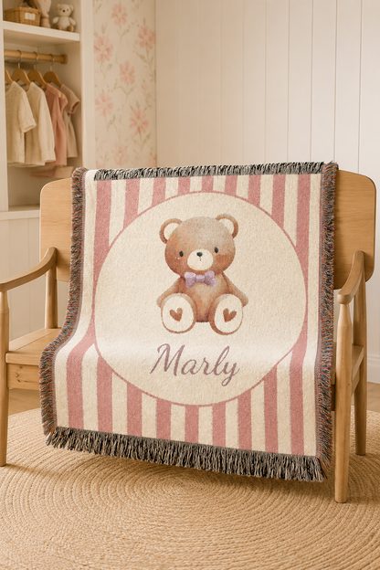 Personalized blush stripe teddy bear blanket draped over a chair in a nursery