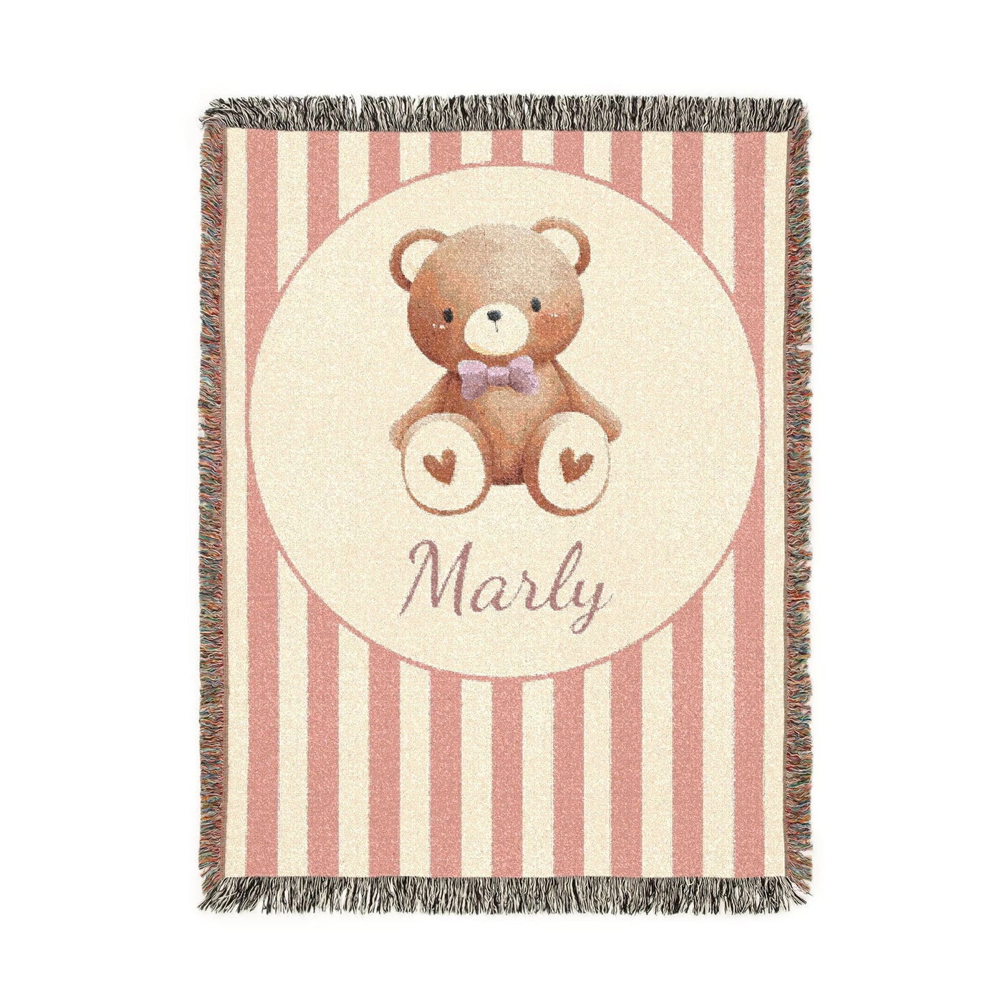Personalized woven baby blanket with a brown teddy bear in a purple bow tie and little hearts in a cream circle on a blush pink and cream stripe, with a name woven in, shown flat