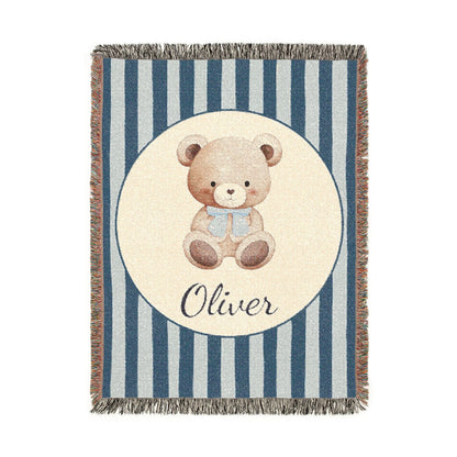 Personalized woven baby blanket with a watercolour teddy bear in a cream circle on a navy and pale blue stripe, with a name woven in, shown flat