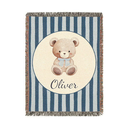 Personalized woven baby blanket with a watercolour teddy bear in a cream circle on a navy and pale blue stripe, with a name woven in, shown flat