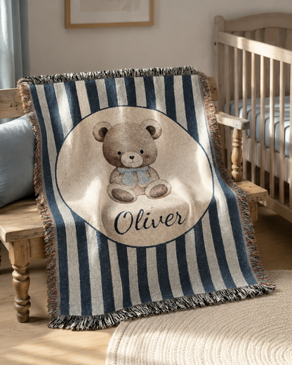 Personalized navy stripe teddy bear blanket over a crib in a bright nursery with framed art