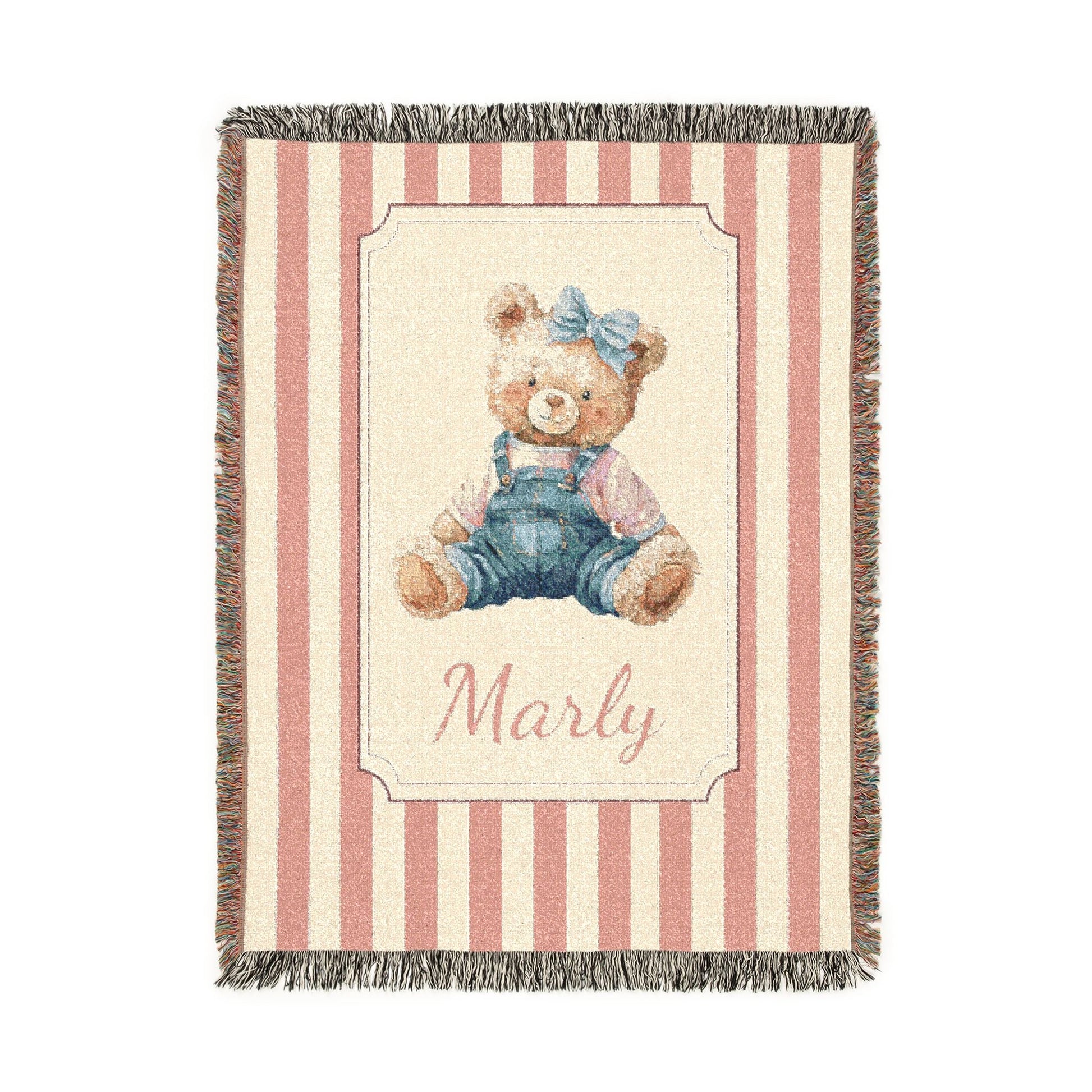 Personalized woven baby blanket with a watercolour teddy bear in dungarees and a blue bow on a pink and cream stripe, with a name woven in, shown flat