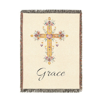 Personalized baptism blanket with a gold floral cross on cream and a name woven in beneath it, shown flat