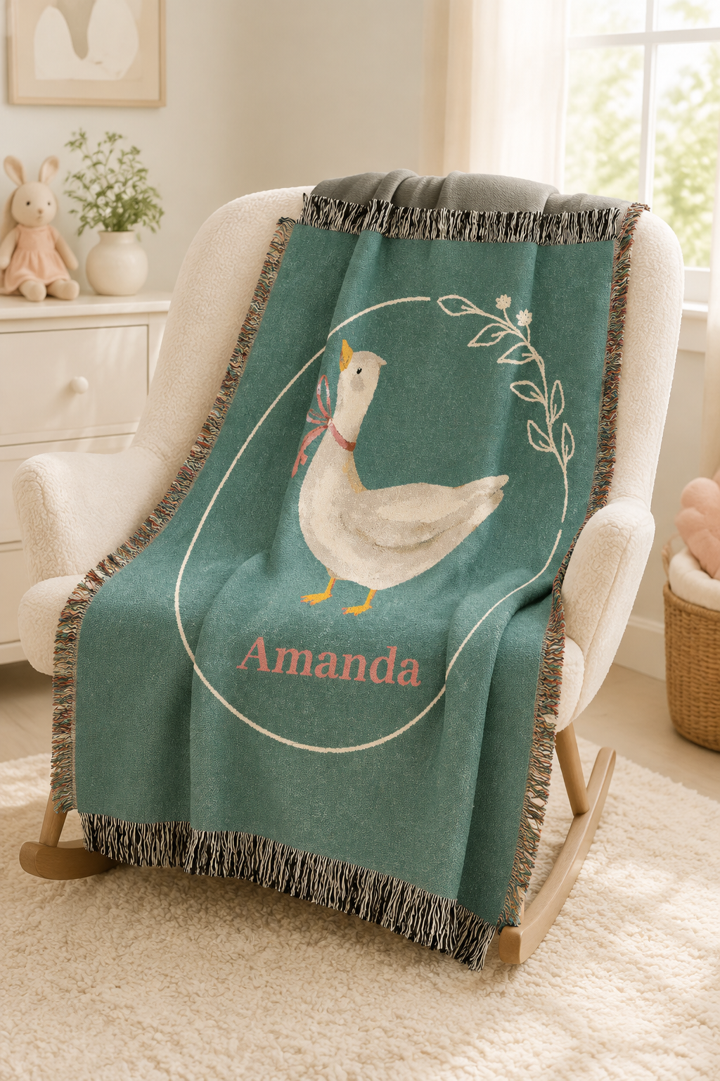 Personalized goose baby blanket over a chair in a bright nursery with framed art