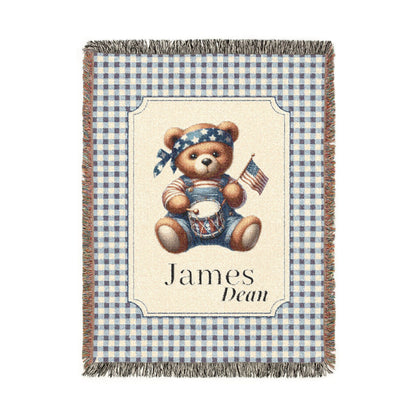 Personalized patriotic teddy bear blanket with a bear in dungarees holding a flag and drum on blue gingham, with a first and middle name woven in, shown flat