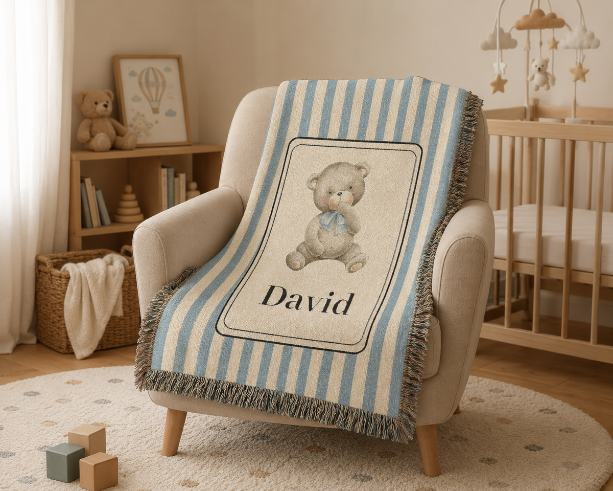 Personalized bear baby blanket over a cream armchair beside a crib with a mobile above
