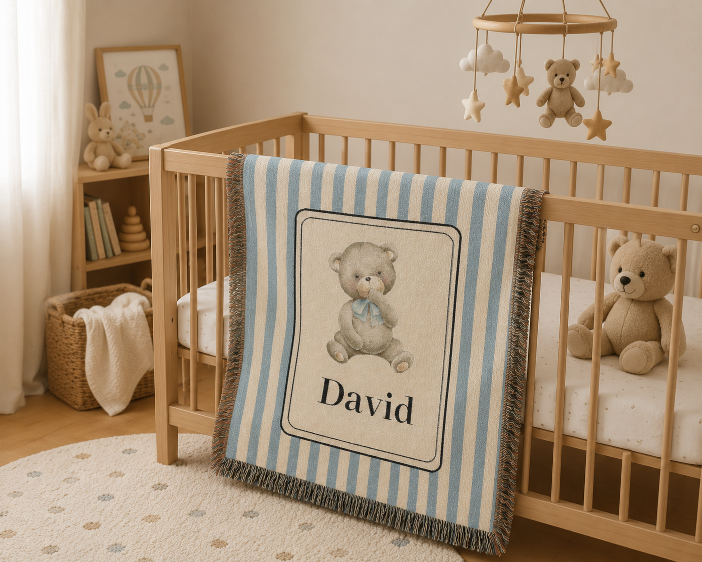 Personalized bear baby blanket draped over a wooden crib in a neutral nursery with a bookcase
