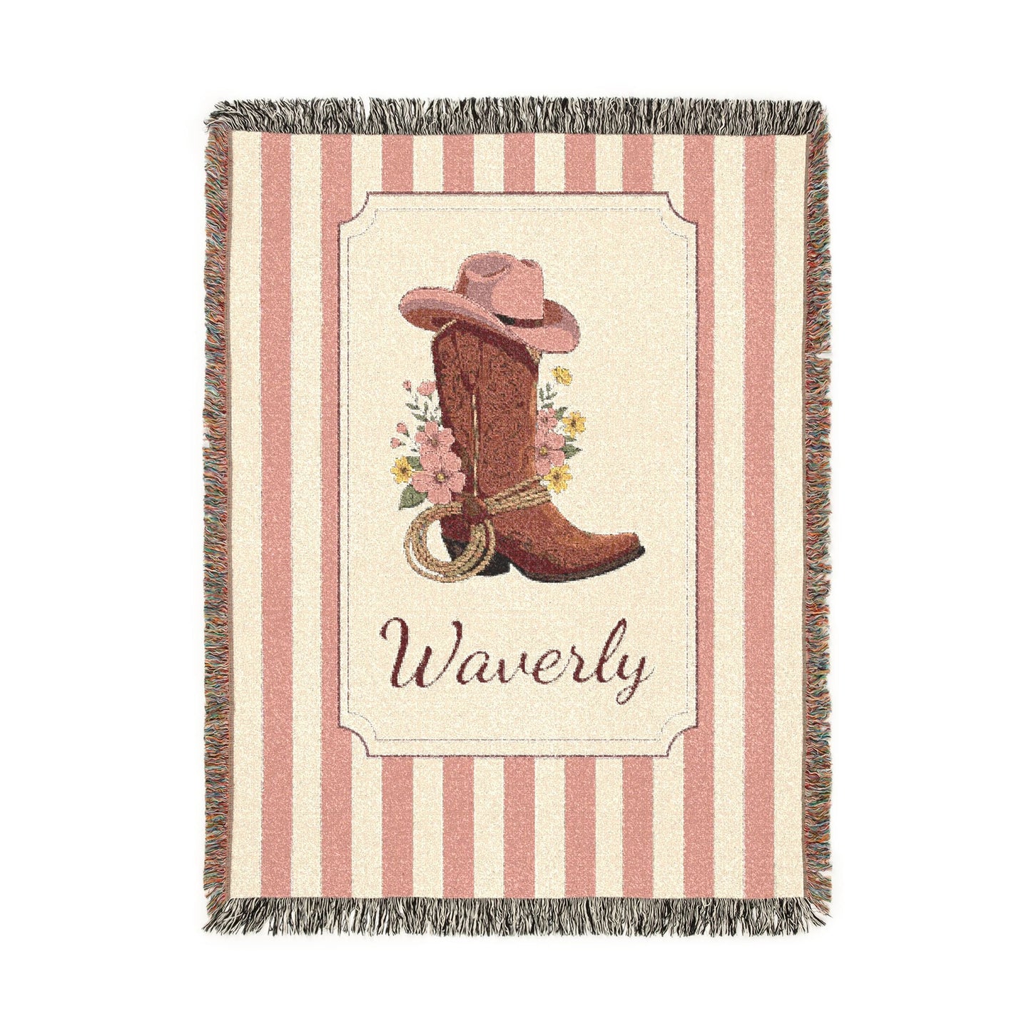 Personalized woven baby blanket with a cowgirl boot, pink hat and wildflowers in a framed panel on a pink and cream stripe, with a name woven in, shown flat