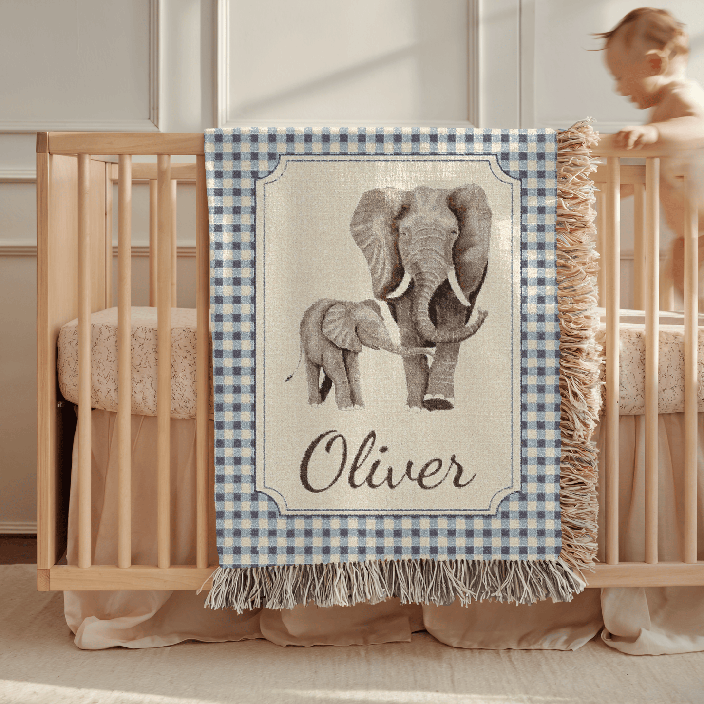 Personalized elephant baby blanket draped over a wooden crib in a neutral nursery