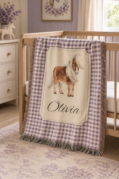 Personalized pony baby blanket over the rail of a crib in a bright nursery