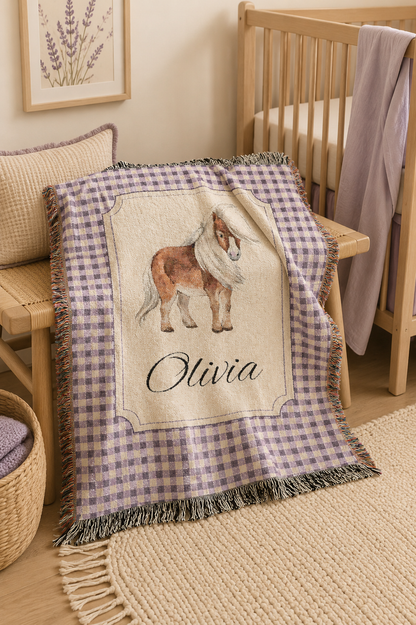Personalized pony baby blanket over a rocking chair beside a crib