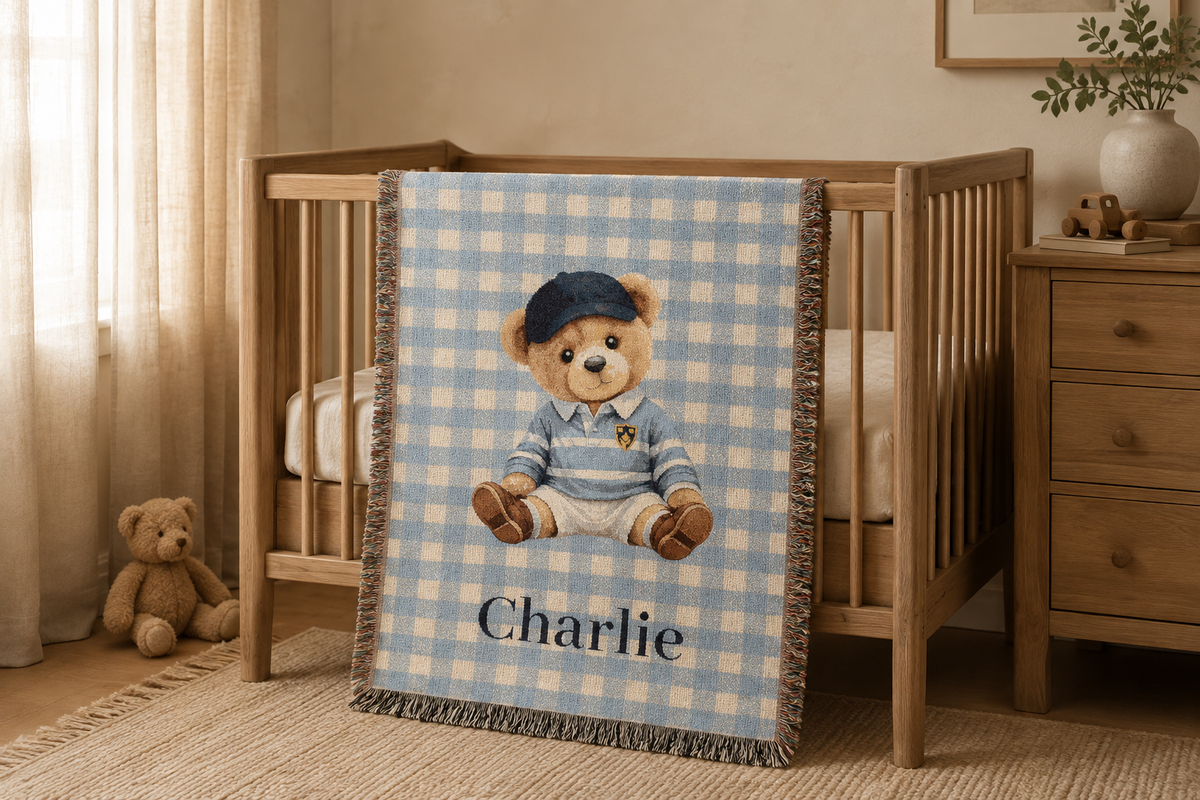 Personalized teddy bear baby blanket draped over a wooden crib in a nursery with a dresser
