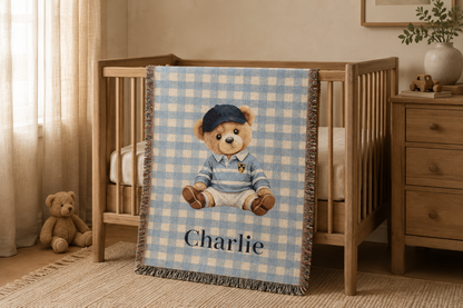 Personalized teddy bear baby blanket draped over a wooden crib in a nursery with a dresser