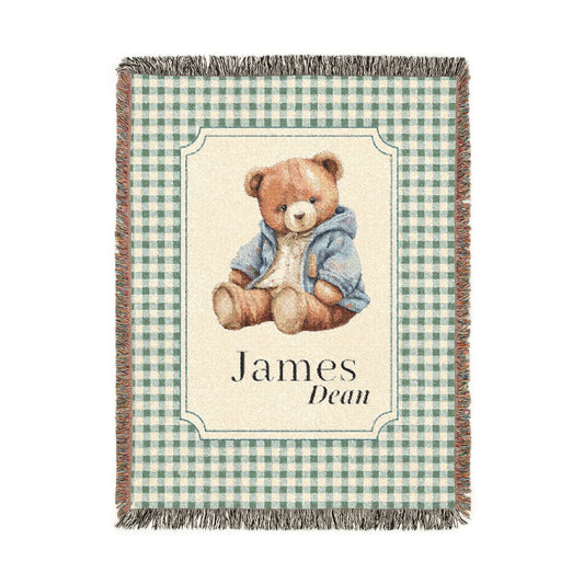 Personalized woven baby blanket with a teddy bear in a blue jacket on sage gingham, with a first and middle name woven in, shown flat