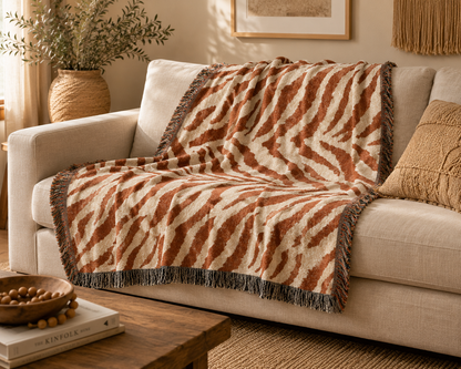 Safari woven blanket draped over a cream sofa in a warm neutral living room