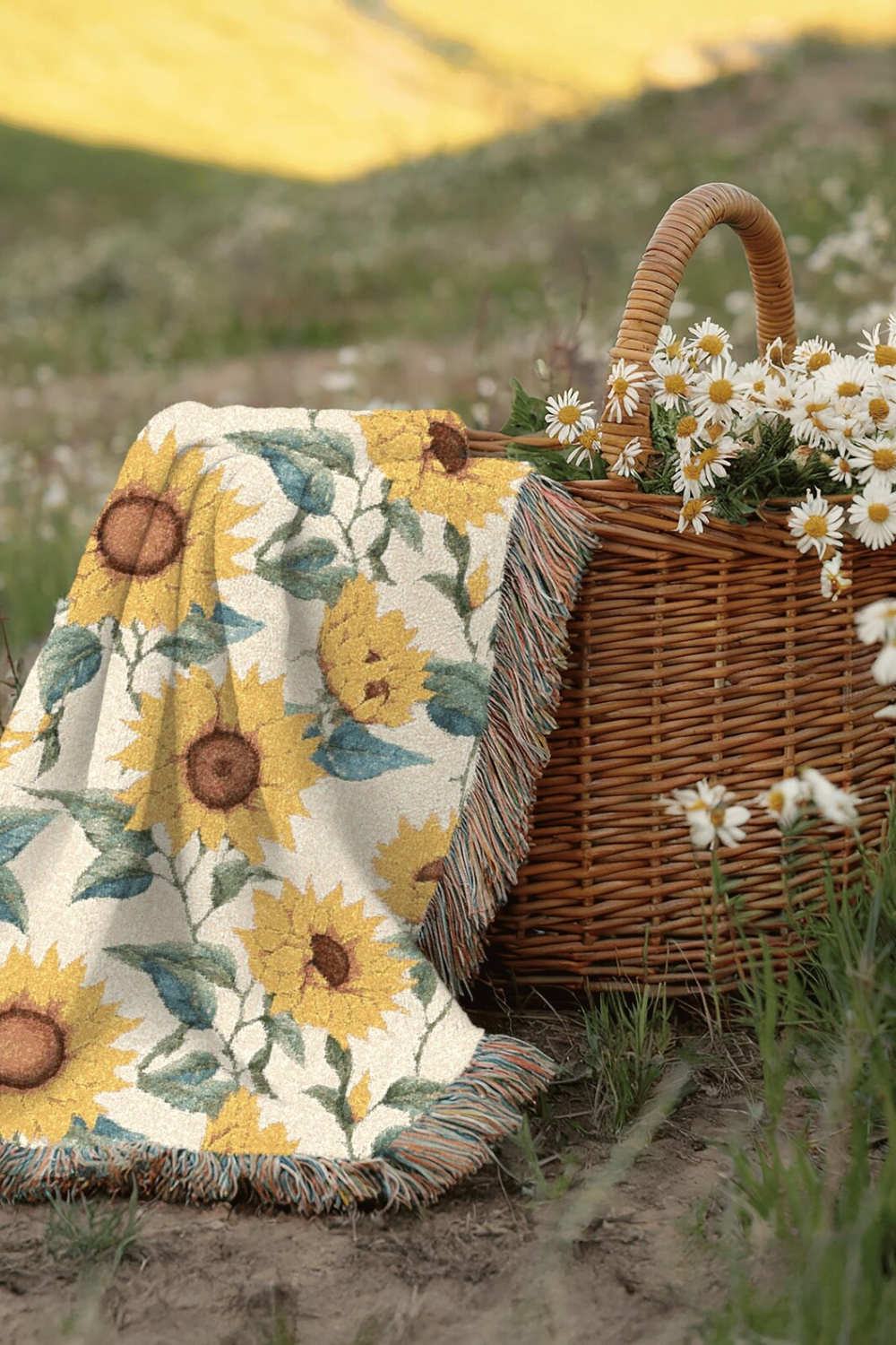 Sunflower woven blanket on the grass with a picnic basket and flowers
