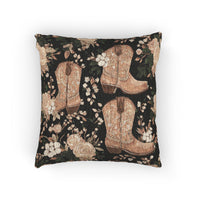 Woven pillow with tan cowboy boots, peach roses and cream blossoms on a black ground, front view