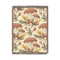 Woodland mushroom woven blanket featuring red-capped toadstools, golden oak leaves and acorns on a cream ground