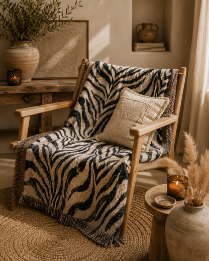 Zebra woven blanket over an armchair with pampas grass and warm lamplight
