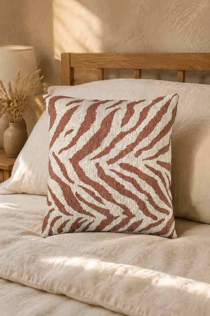 Terracotta zebra pillow on a bed in warm sunlight